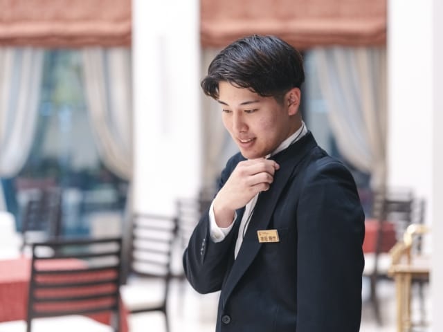 パーティ会場でピンマイクに向かって話す男性スタッフの写真