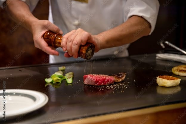 鉄板の上の肉に胡椒を振る写真